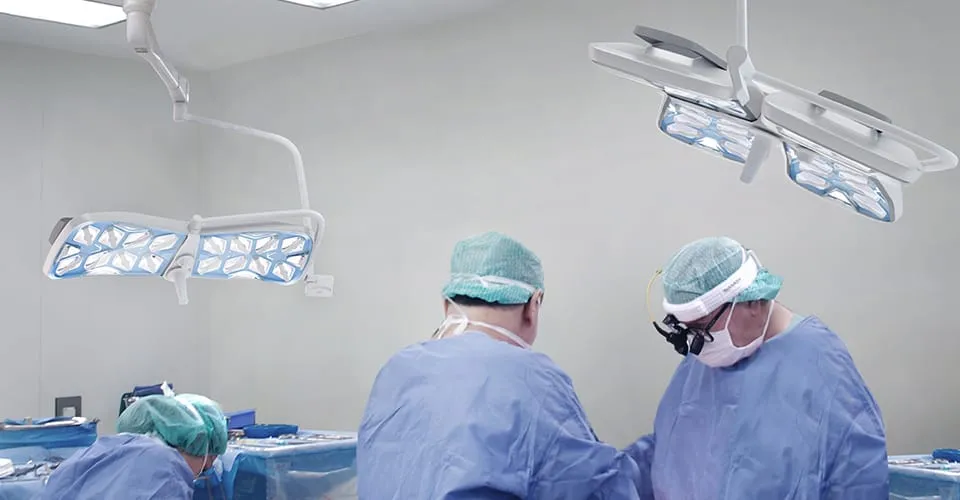 Zwei Chirurgen operieren unter APOLLO-Laseroperationsleuchten an Deckenarmen