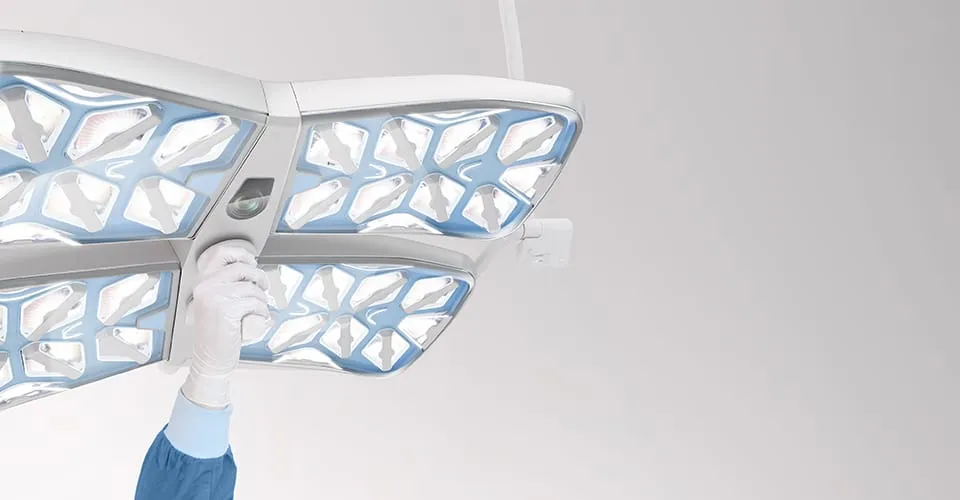 Behandschuhte Hand justiert die APOLLO-Operationsleuchte von unten, Vier-Modul-Konfiguration mit Laseroptiken