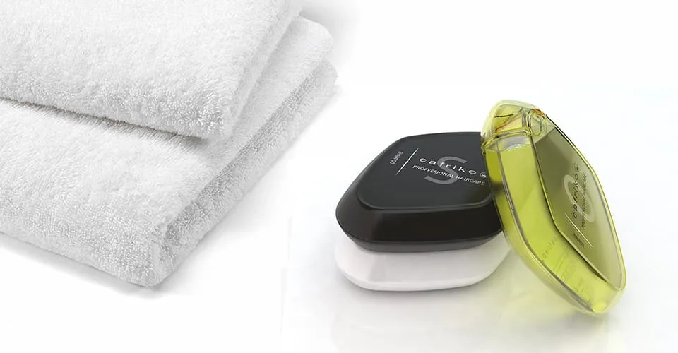 Gefaltete weiße Spa-Handtücher neben gestapelten CAFRIKO Conditioner- und Haaröl-Flaschen