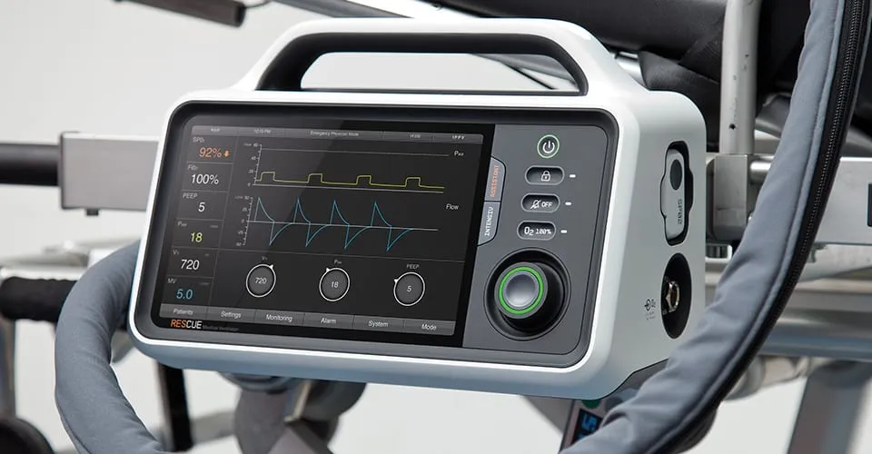 RESCUE-Beatmungsgerät am Transportbett-Geländer im Intensivmediziner-Modus mit Kurvendaten auf dem Display