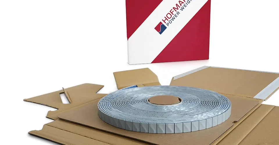 SPEEDBOX cardboard dispenser opened flat revealing a coiled roll of adhesive balance weights