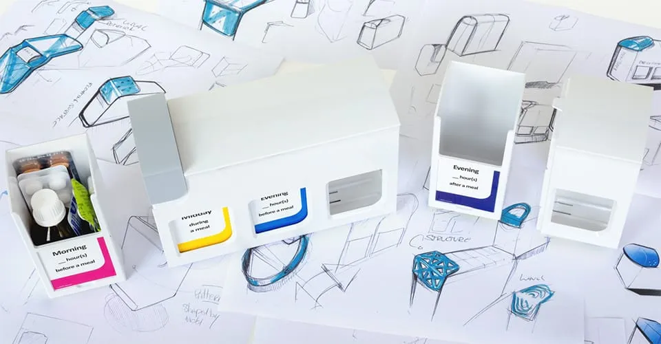 mediTimer-Prototyp mit farbcodierten Tageszeit-Fächern auf frühen Designskizzen