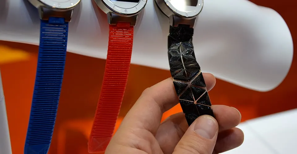 Three 3D-printed wristbands for Covestro Watch wearable in blue, red, and black held at exhibition