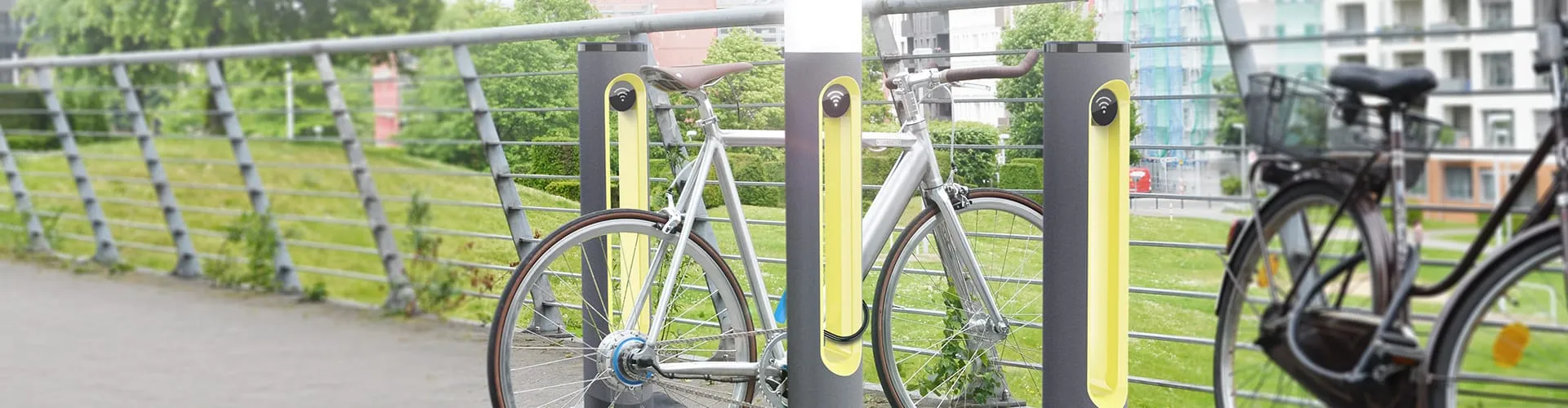 SMARTPOLE charging stations installed along a bridge railing with bicycles parked in an urban environment