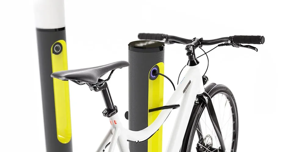 White e-bike parked and connected to a SMARTPOLE charging station with additional poles visible in background