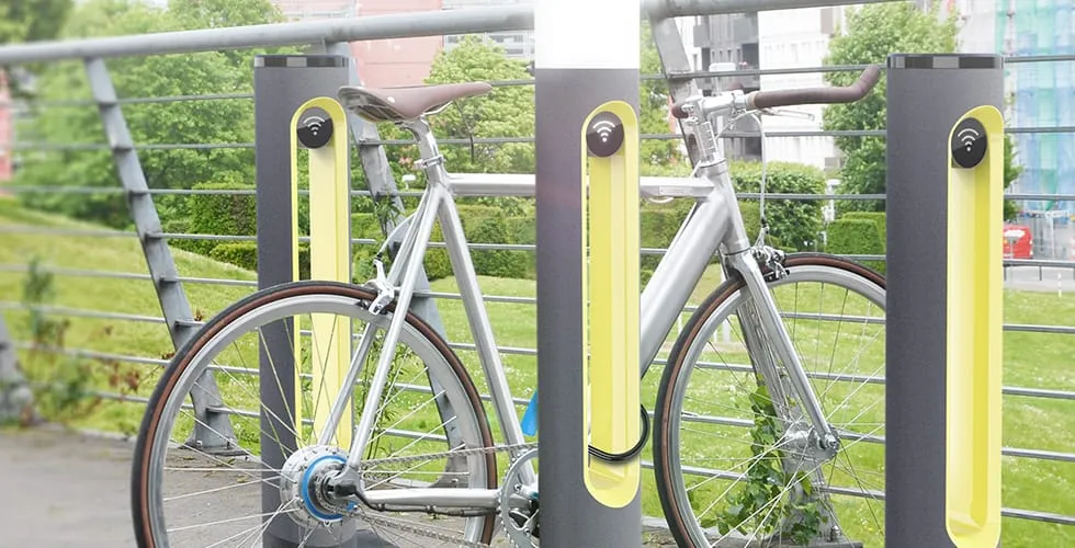 Two SMARTPOLE charging stations installed at a bridge railing with bikes parked in an urban setting